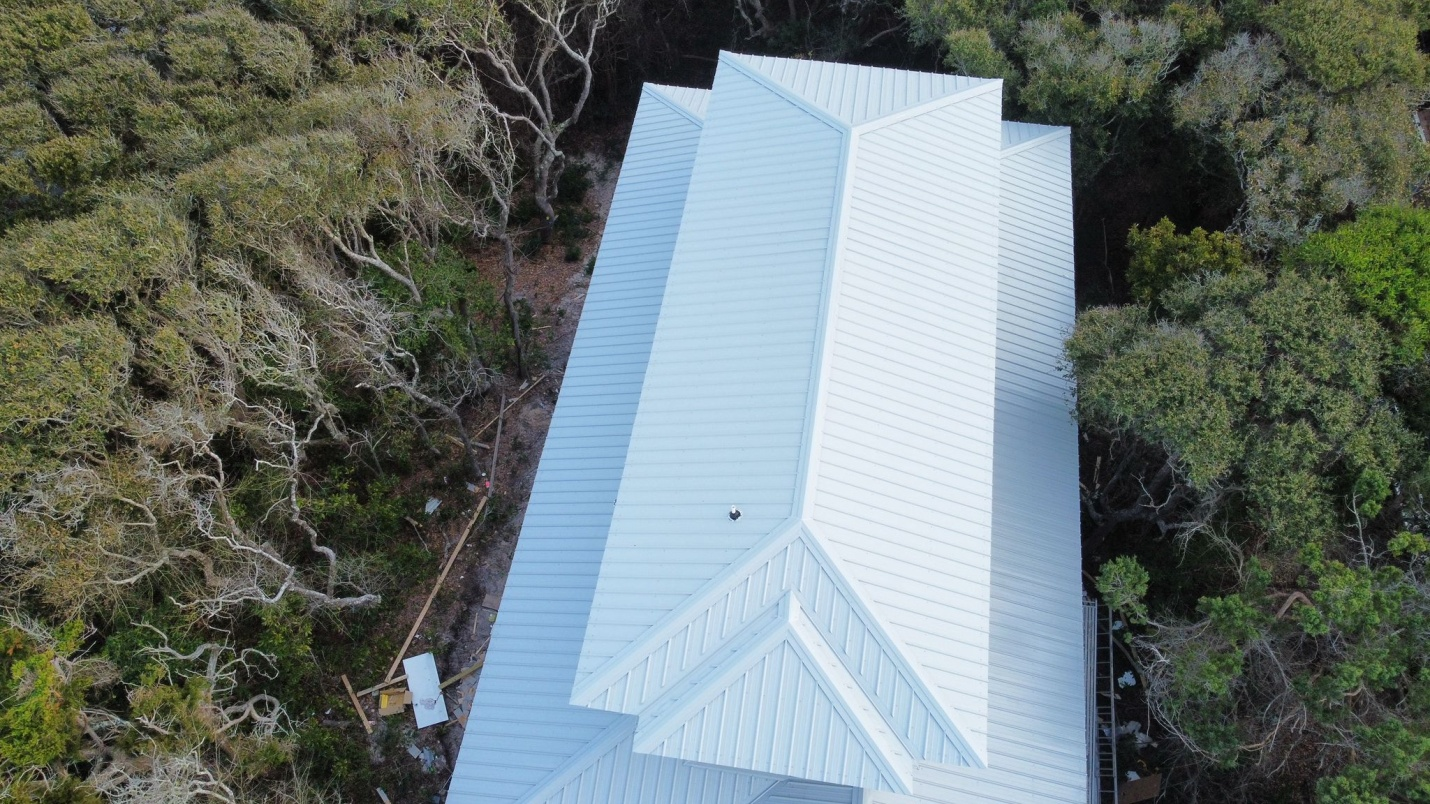 A Polar White roof on a white house surrounded by foliage